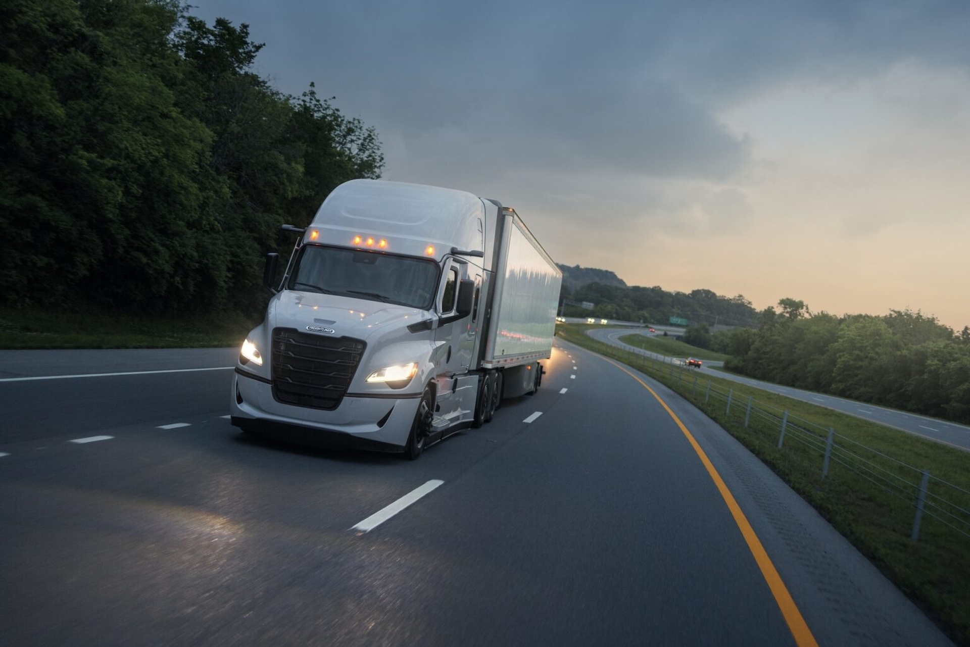 Freightliner Cascadia pulling a dry van on the interstate at dusk